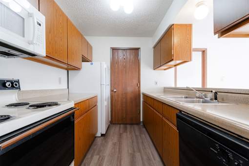 A kitchen with a white stove top oven and black dishwasher at Rosemont Place Apartments, Des Moines