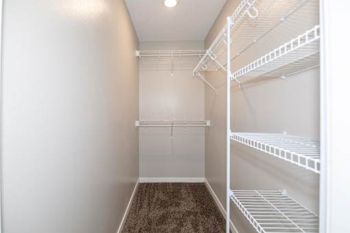a spacious walk in closet with white shelves and a mirrored closet door at Rosemont Place Apartments, Iowa, 50320