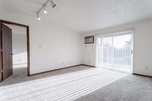 A room with a carpeted floor and a sliding glass door at Rosemont Place Apartments, Des Moines, IA