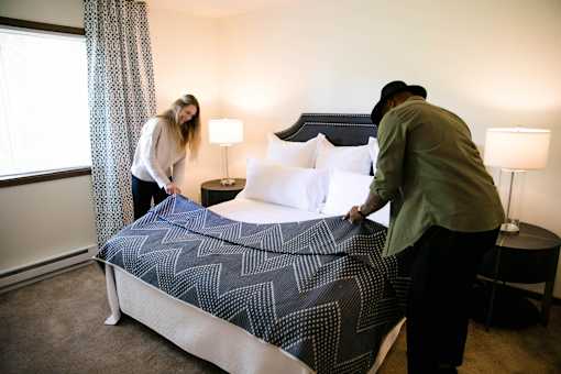 a couple making a bed in a hotel room at Rosemont Place Apartments, Des Moines, IA