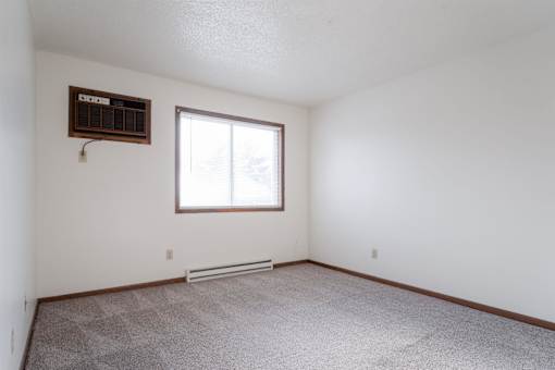 A room with a window and a carpeted floor. at Rosemont Place Apartments, Des Moines