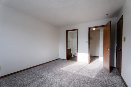 A room with a carpeted floor and a door on the right at Rosemont Place Apartments, Des Moines, 50320