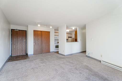 A spacious living room with a carpeted floor and white walls. at Rosemont Place Apartments, Des Moines, Iowa