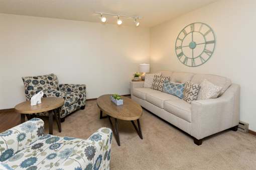 a living room with couches and chairs and a clock on the wall at Rosemont Place Apartments, Des Moines, Iowa