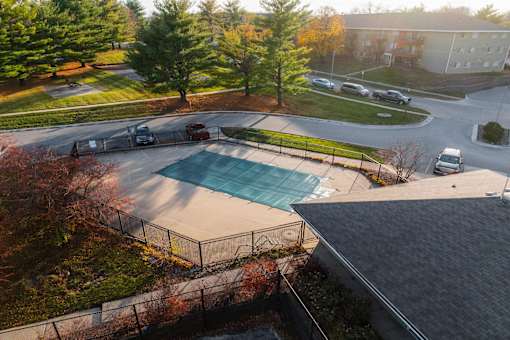 A swimming pool surrounded by a fence and trees. at Rosemont Place Apartments, Des Moines, IA