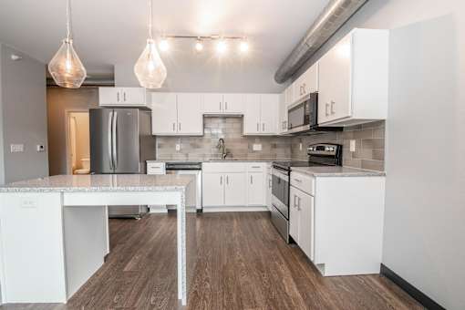 a white kitchen with white cabinets and stainless steel appliances at Soll, Des Moines Iowa   