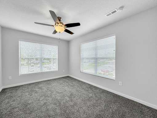 an empty bedroom with a ceiling fan and two windows at Soll, Des Moines, IA 50312  