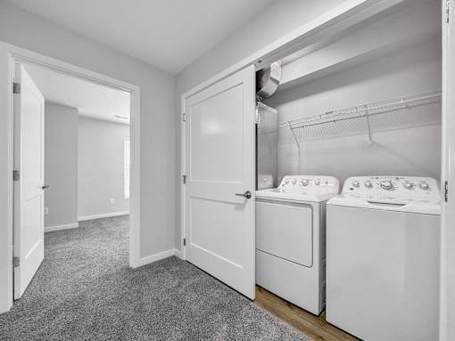 a white laundry room with two washes and a dryer at Soll, Des Moines, IA  
