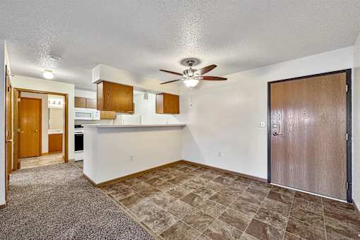 an empty living room with a kitchen and a ceiling fan at Somerset Apartments, Iowa, 50315