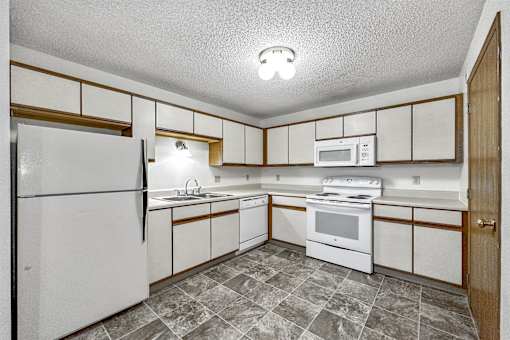 a kitchen with white appliances and wooden cabinets at Somerset Apartments, Des Moines, IA, 50315
