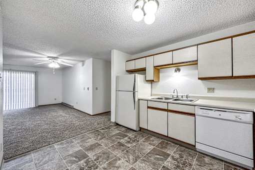 A kitchen with white appliances and a tiled floor. at Somerset Apartments, Des Moines, IA