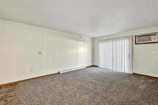 A room with a carpeted floor and a window with blinds at Somerset Apartments, Des Moines, Iowa