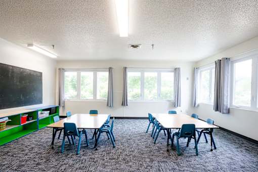 a classroom with tables and chairs and a chalkboard on the wall at Sutton Hill Apartments, Des Moines, IA, 50320