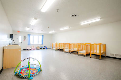 a multipurpose room with children cribs and a baby play area at Sutton Hill Apartments, IOWA