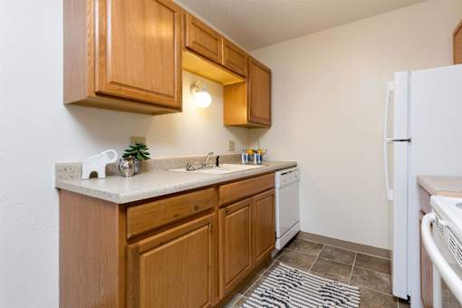 A kitchen with wooden cabinets and a white fridge at Sutton Hill Apartments, Des Moines, IA, 50320