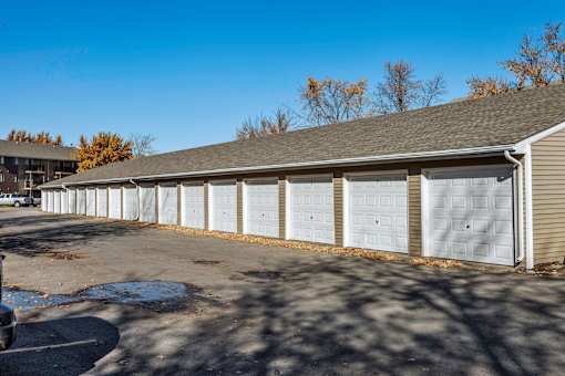 A long building with a grey roof and white garage doors at Sutton Hill Apartments, Des Moines, IA