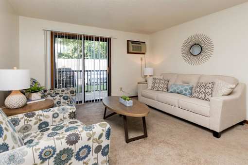 a living room with a couch and a chair and a sliding glass door at Sutton Hill Apartments, IOWA