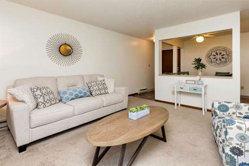 A living room with a couch, coffee table, and mirror at Sutton Hill Apartments, IOWA, 50320