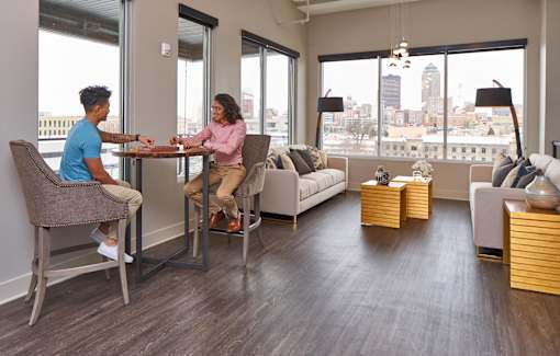 Two people sitting at a table in a room with a view of the city at Velocity Apartments, Iowa, 50309