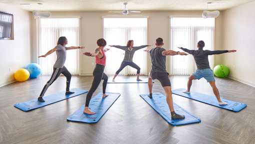 a group of people practicing yoga on yoga mats in a yoga studio at Velocity Apartments, Des Moines, IA