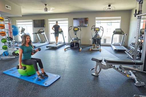 a woman on a stability ball in a gym with other exercise equipment at Velocity Apartments, Des Moines