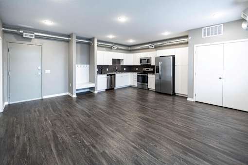 an empty living room with a refrigerator and a sink at Velocity Apartments, Des Moines