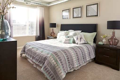 a bedroom with a bed and a dresser and a window at Velocity Apartments, Iowa