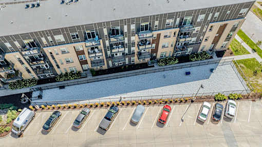 an aerial view of a parking lot with cars in front of an apartment building at Velocity Apartments, Iowa