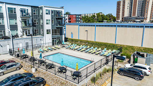 a swimming pool at an apartment complex with cars parked around it at Velocity Apartments, Des Moines, IA, 50309