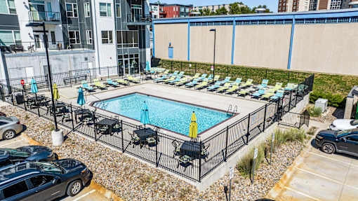 a swimming pool with lounge chairs in front of a building at Velocity Apartments, Des Moines, IA
