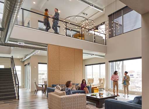 A group of people are standing in a spacious living room at Velocity Apartments, Des Moines, Iowa
