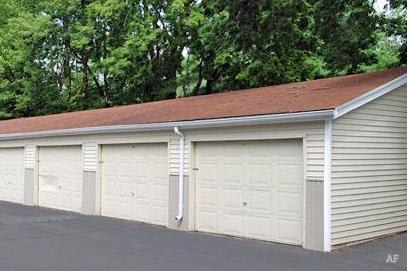 a white garage with white doors and a red roof at Foxwood Apartments, Indianola, IA 50125  