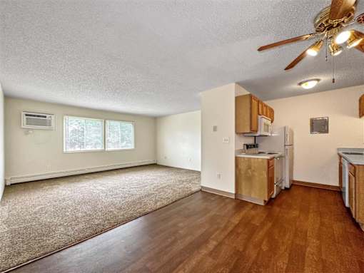 an empty living room with a kitchen and a ceiling fan at Foxwood Apartments, Indianola, 50125  