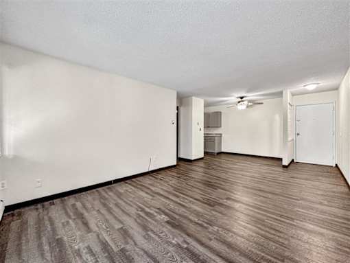 an empty living room with white walls and wood flooring at Foxwood Apartments, Indianola  