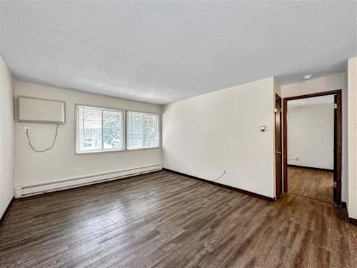 an empty living room with white walls and wood floors at Foxwood Apartments, Iowa  