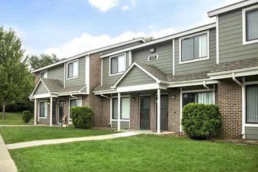 A row of houses with green lawns in front at Hunters Run Apartments, IA, 50208