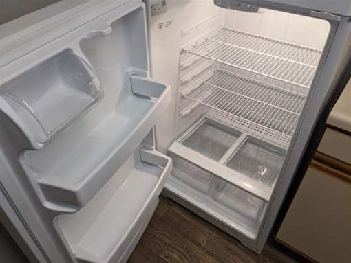 A white refrigerator with the door open showing the shelves and drawers at Hunters Run Apartments, Newton