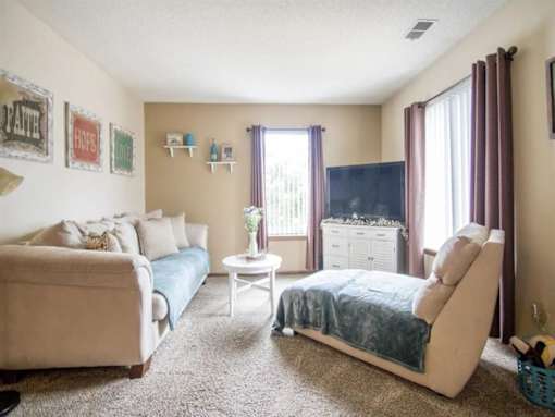 A living room with a couch, chair, and a small table at Hunters Run Apartments, Iowa, 50208