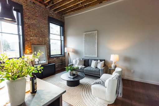 A living room with a grey couch and a white chair.at Plant 1 Lofts, N. Newton, 50208  