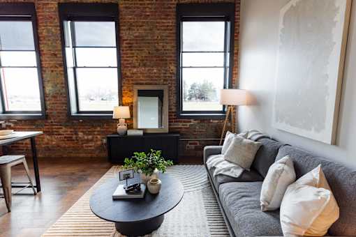 A living room with a grey couch and a black coffee table.at Plant 1 Lofts, Iowa   