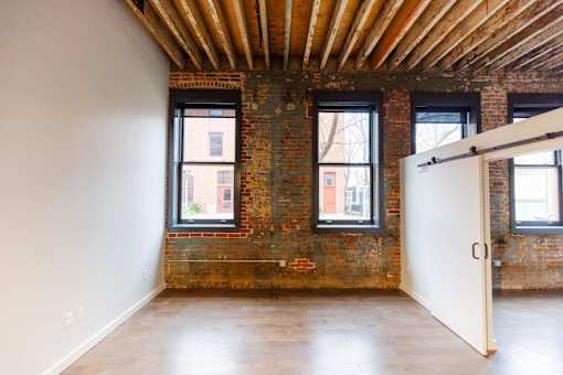 A room with a white door and windows with a brick wall.at Plant 1 Lofts, N. Newton Iowa   
