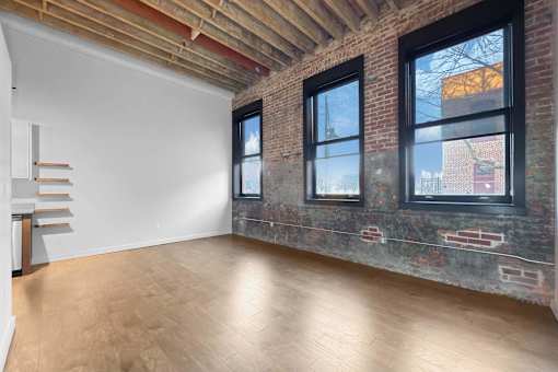 A room with wooden floors and a white wall with a window.at Plant 1 Lofts, Iowa   