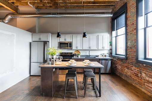 A kitchen with a table and chairs in the middle of it.at Plant 1 Lofts, N. Newton, IA  