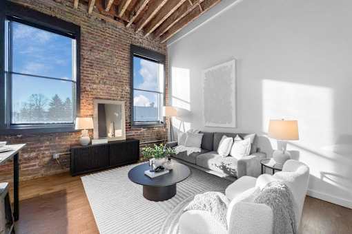 A living room with a brick wall and a fireplace.at Plant 1 Lofts, N. Newton, IA 50208  
