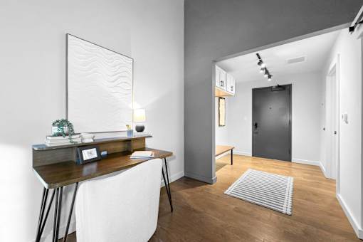 A modern home office with a desk, chair, and a large mirror on the wall.at Plant 1 Lofts, N. Newton  