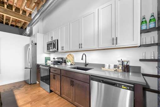 A kitchen with a stainless steel dishwasher and a refrigerator.at Plant 1 Lofts, N. Newton Iowa   