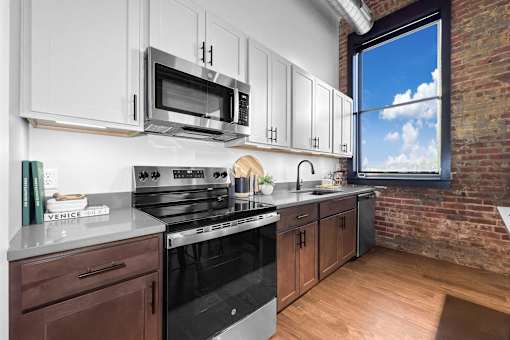 A kitchen with a black stove top oven and a microwave above it.at Plant 1 Lofts, N. Newton, 50208  