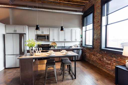 A kitchen with a table and chairs in front of a brick wall.at Plant 1 Lofts, N. Newton, 50208  