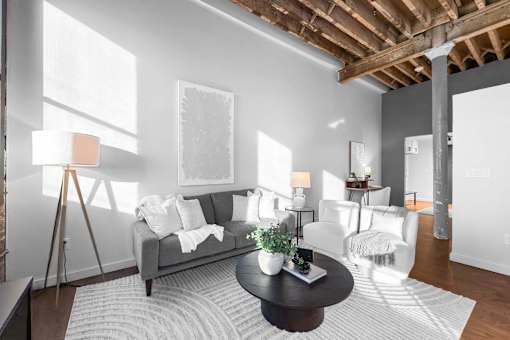 A living room with a grey couch, a black coffee table, and a white rug.at Plant 1 Lofts, N. Newton, 50208  