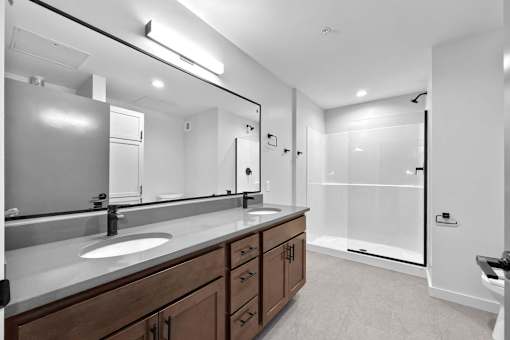 A bathroom with a sink, mirror, and a walk-in shower.at Plant 1 Lofts, Iowa   